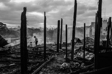 Residents walk amongst the burnt out remains of shacks that were destroyed by a fire in the northern part of Sao Paulo. More than 2 million people live in precarious communities like this one in Sao P...