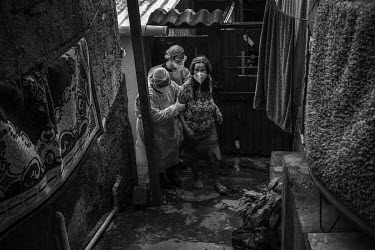 Nurses from the emergency medical service help Anísia Moreira dos Santos, 74, suspected of having Covid-19, to walk from her home to the ambulance in the slum of Paraisopolis, south of Sao Paulo,
