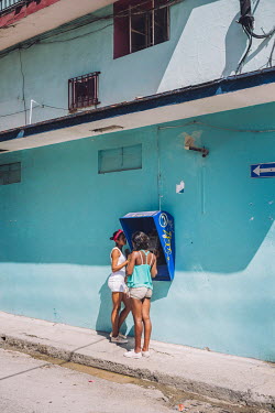 Two young women making a call from a streetside telephone booth.