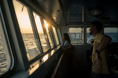 First mate Nacho Suaje and deckhand Waya Maweru on board the Greenpeace vessel Arctic Sunrise keep watch at sunset in the mid-Atlantic ocean.