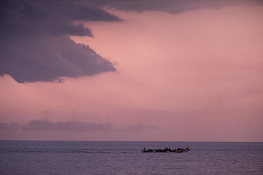 Fishing canoes (pirogues) return to shore near Dakar at sunset.