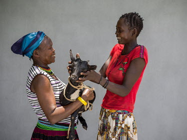 Kodet Theresa (46) (L) gives a goat to a villager as part of a community breeding scheme.
