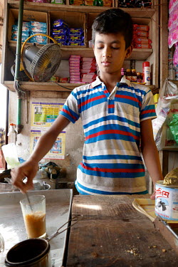 Shihab Uddin (14) prepares tea in the small tea shop where he sells cigarettes, makes tea and paan (bitter leaves with local tobacco), working from 6am to 12pm. His impoverished parents sent him to th...