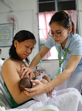 A member of the paediatric medical staff helps a mother breastfeed her newborn twins on a maternity ward at the Fabella Hospital.