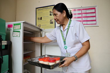 A member of the paediatric medical staff collects expressed breastmilk from a fridge at the Fabella Hospital.