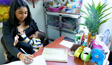 Lucky Chocolate, Thiri Thet Naing, (22), a business woman, breastfeeds her 15 month old baby girl Victoria while working in her office.