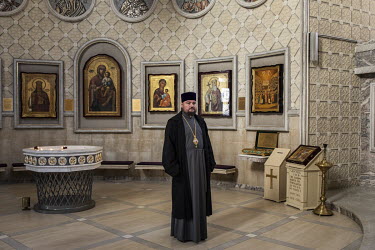 Metropolitan Olexander Drabinko stands in front of a wall in his church that is hung with icons. He is one of the priests who defected from the Moscow-linked Orthodox church to the new Orthodox Church...