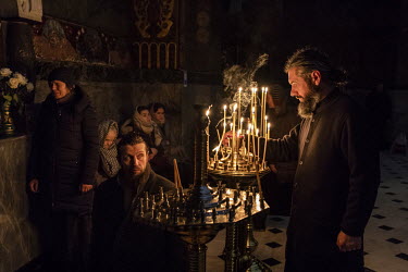 A man lights a votive candle as worshippers attend an evening service in one of the churches at the Kiev-Pechersk Lavra monastery, which remains under the control of Moscow despite the split between t...