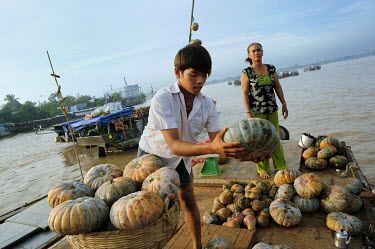 A boy moves pumpkins sold from the deck of a boat in the Mekong Delta.