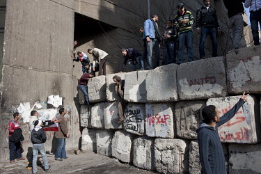 People gather at a concrete wall, erected by the military to protect the Ministry of Interior from attacks, on the first anniversary of the 25 January Revolution which brought down the Mubarak regime.