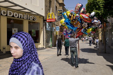 A man selling novelty balloons walks past a branch of McDonald's on Ledras Street.