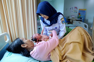 A health worker helps a mother breastfeed her new born baby.
