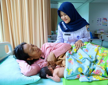 A health worker helps a mother breastfeed her new born baby.