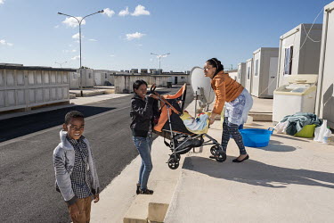 Two women lift a buggy up a flight of steps leading to their 'container house' in the 'Tent Village Open Centre'. A container house accomodates up to two families or eight individuals. Most residents...