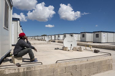 A migrant sits in front of a 'container house' in the 'Tent Village Open Centre'. A container house accomodates up to two families or eight individuals. Most residents are Africans, predominantly from...