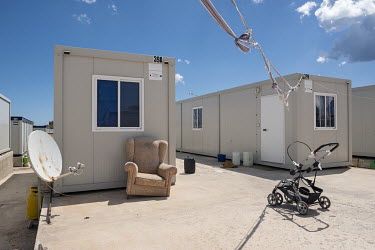 An arm chair, buggy and satellite dish in front of a 'container house' in the 'Tent Village Open Centre'. A container house accomodates up to two families or eight individuals. Most residents are Afri...