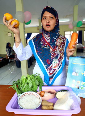 A health worker gives a demonstration to new mothers on healthy food and breastfeeding.