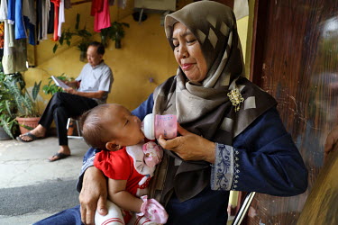 A grandmother feeding her grandaughter with expressed milk while taking care of her while the mother is at work.