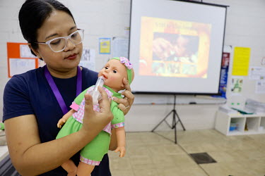 A health education worker uses a doll to give a class of pregnant women a breastfeeding demonstration.