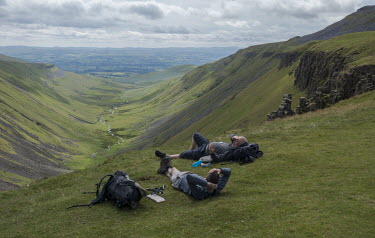 Walkers rest on a hill top on High Cup Nick on the Pennine Way in Cumbria