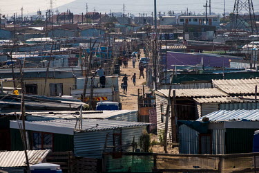 People walk along an alleyway, between shacks made from corrugated zinc, in an over-crowded informal settlement that its residents have named Malema, after the leader of the Economic Freedom Fighters...