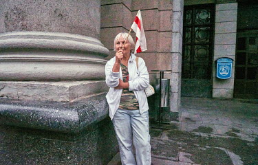 An elderly woman waves a red and white flag, adopted by the Belarusian opposition,as she watches from the sidelines a huge rally of around 100,00 protesters in the centre of Minsk demanding the resign...