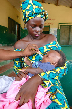 A woman holds her baby while a health worker administers an oral vaccination at the Mvouti Health Centre.