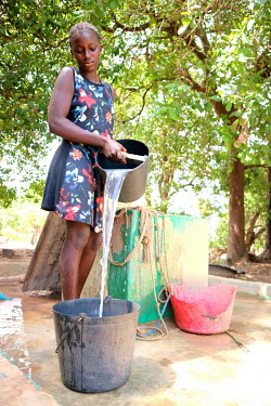 A girl collects water from a communal well beside the home where she lives.