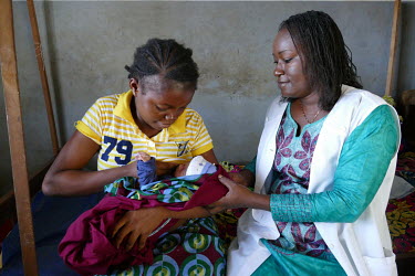 A health worker helps a new mother breastfeed her baby in the village health centre's maternity ward.