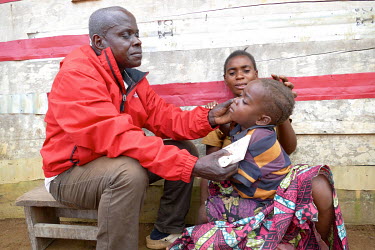 A health worker examines a child from the Loukana Indigenous Community for possible malaria infection.