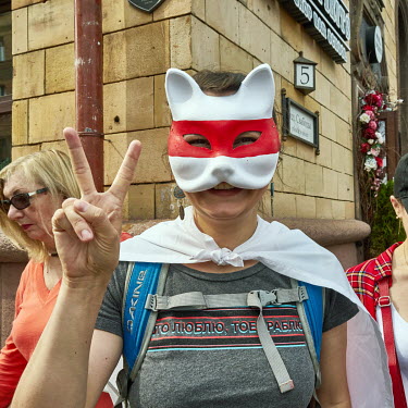 A protestor in a painted red and white cat mask.