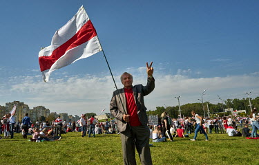 A man holds a red and white flag, adopted by the Belarusian opposition, during a rally where tens of thousands of people gathered in the city centre demanding the resignation of the authoritarian pres...