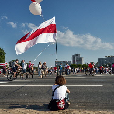 A young woman with a red and white flag, adopted by the Belarusian opposition, sits at the roadside during a one of the ongoing mass protests in the city centre where the demand was for the resignatio...