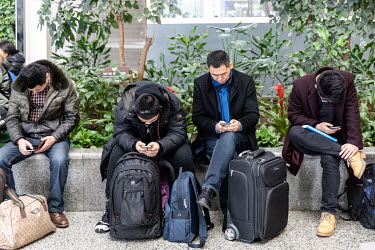 Travellers look at their smartphones while waiting for trains on the crowded main concourse at Shanghai Hongqiao Railway Station ahead of the Lunar New Year annual migration that sees hundreds of mill...