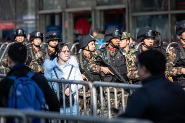 An armed security patrol makes its way through crowds of travellers waiting for trains on the main concourse at Shanghai Hongqiao Railway Station ahead of the Lunar New Year annual migration that sees...