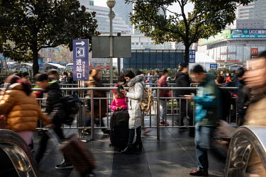 A woman and child stand still among the crowds of moving travellers heading into Shanghai Hongqiao Railway Station ahead of the Lunar New Year annual migration that sees hundreds of millions of people...