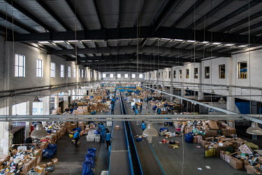 Piles of packages and a sorting conveyer belt in the unloading area at a ZTO Express Inc. facility. Package delivery billionaires, including the founder of ZTO Express, have seen their fortunes swell...
