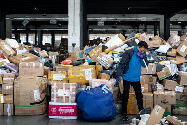 An employee stands in front of a pile of parcels in an unloading area at a ZTO Express Inc. sorting facility. Package delivery billionaires, including the founder of ZTO Express, have seen their fortu...