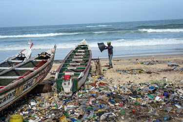 Waste plastic surrounds a fishing pirogue moored on a beach in the Guet Ndar district.