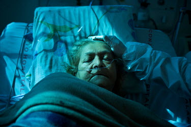 A nurse comforts a critically ill, elderly female patient, suffering from COVID-19, who is lying in a bed in the intensive care unit of the Hospital Geral do Mandaqui.