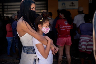 A woman and a girl wait in line for food aid at a distribution facility in the Paraisopolis favela that was set up to offer relief during the coronavirus crisis.