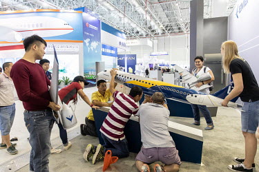 Workers install a model of an Embraer E190-E2 passenger jet at the China International Aviation & Aerospace Exhibition.