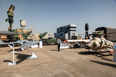 A security guard stands in the midst of a display featuring various Chinese made military drones or Unmanned Arial Vehicles (UAV), missile and rocket launchers, and radar equipment at the China Intern...