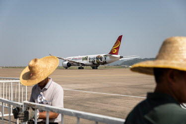 Workers errect a fence near a Boeing 787 passenger jet, belonging to China's Hainan Airlines, taxis down a runway at the China International Aviation & Aerospace Exhibition.