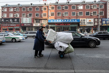A man pushes a cart loaded with sacks full of recyclable material down a street in the city centre.