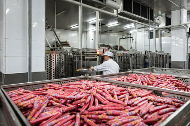 An employee operates a machine while working on a production line making 'Shuanghui' branded sausages from imported pork meat, supplied by Smithfield Foods Inc., at a WH Group Ltd. facility. As China...