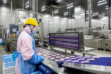 A factory employee monitors sliced ham made from imported pork meat, supplied by Smithfield Foods Inc., on a production line at a WH Group Ltd. facility that processes the pork into ham. As China proh...