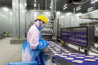A factory employee monitors sliced ham made from imported pork meat, supplied by Smithfield Foods Inc., on a production line at a WH Group Ltd. facility that processes the pork into ham. As China proh...