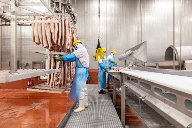 Production line employees hang sides of imported pork belly, supplied by Smithfield Foods Inc., onto racks during the making of bacon at a WH Group Ltd. facility. As China prohibits imports of process...