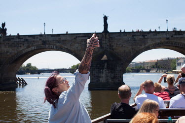A woman on a Vltava River boat trip takes a selfie portrait as the tour is about to go underneath the Charles Bridge.
